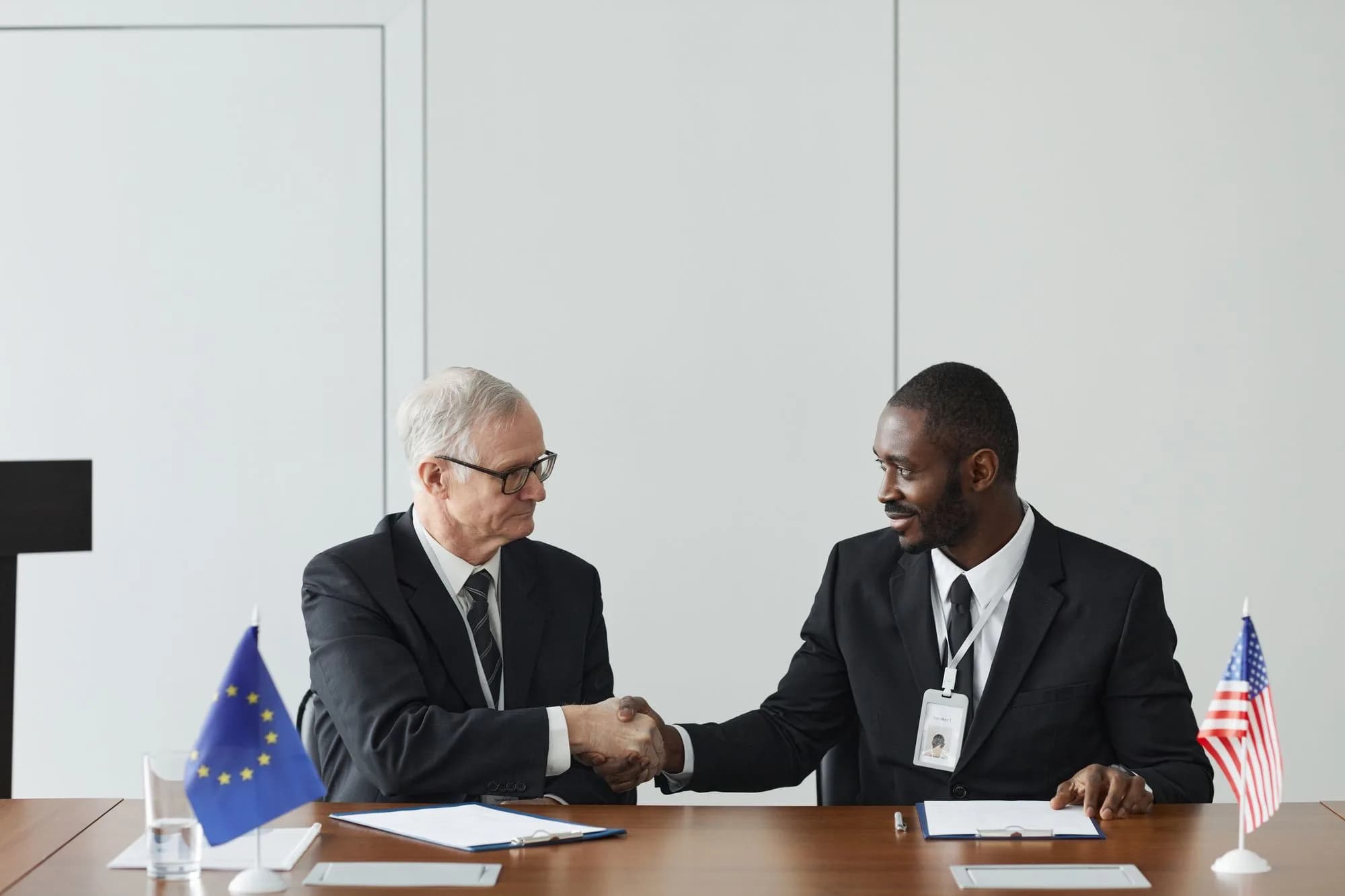 International executives shaking hands during a formal meeting with national flags.