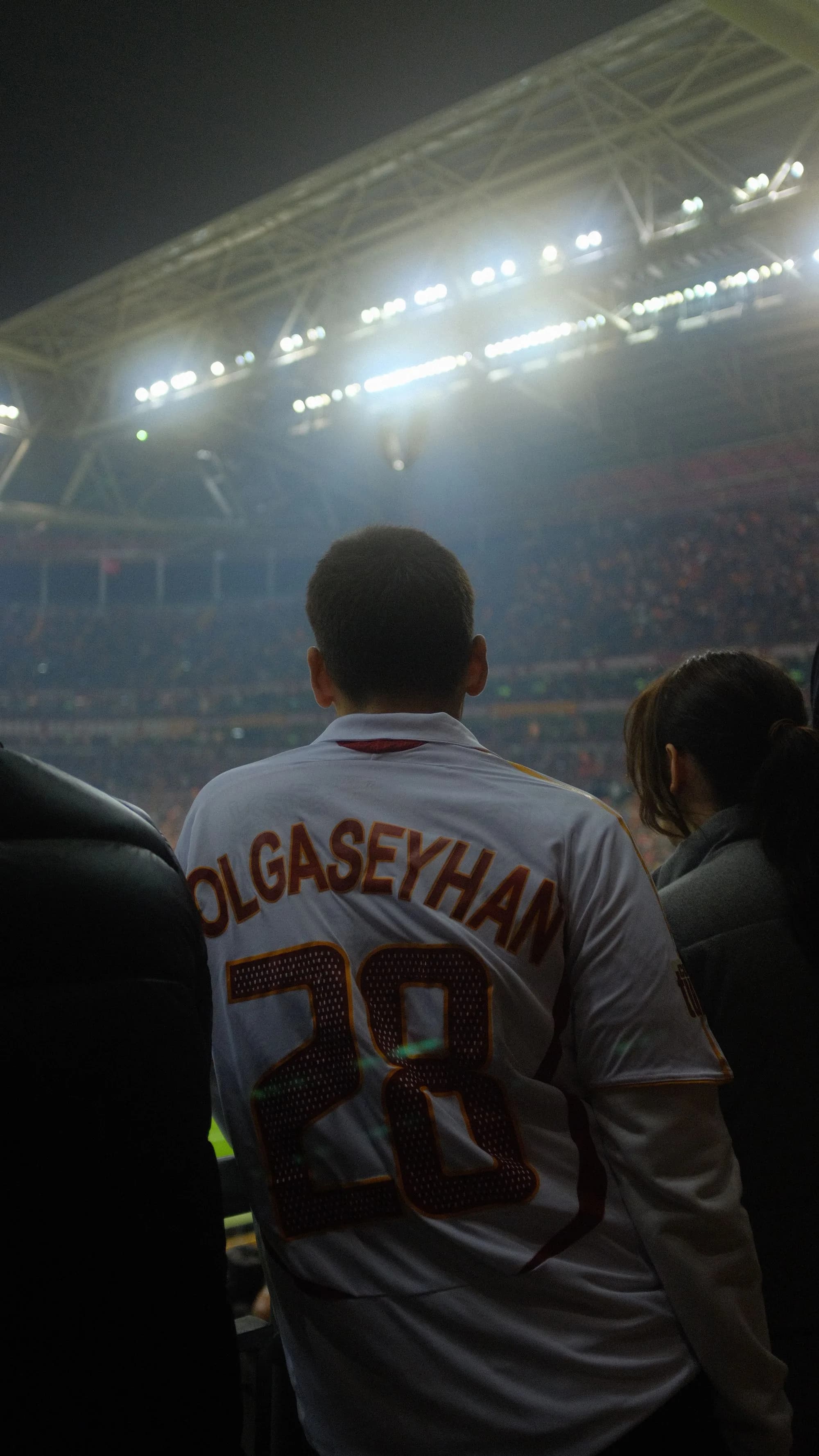Sports spectators watching a major night event beneath stadium lighting.