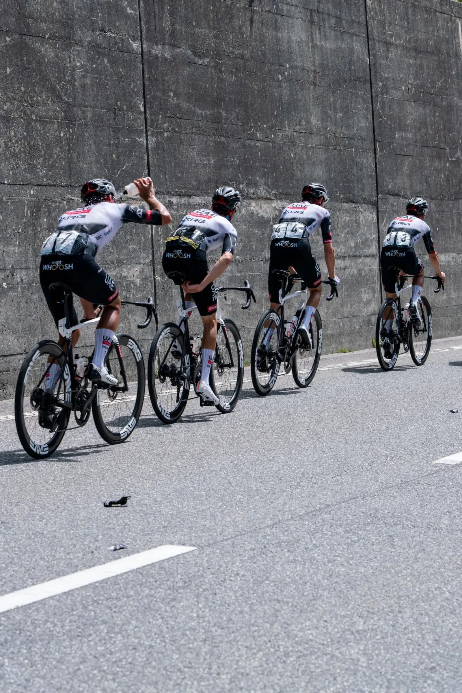 Professional cycling peloton racing together on an urban road.