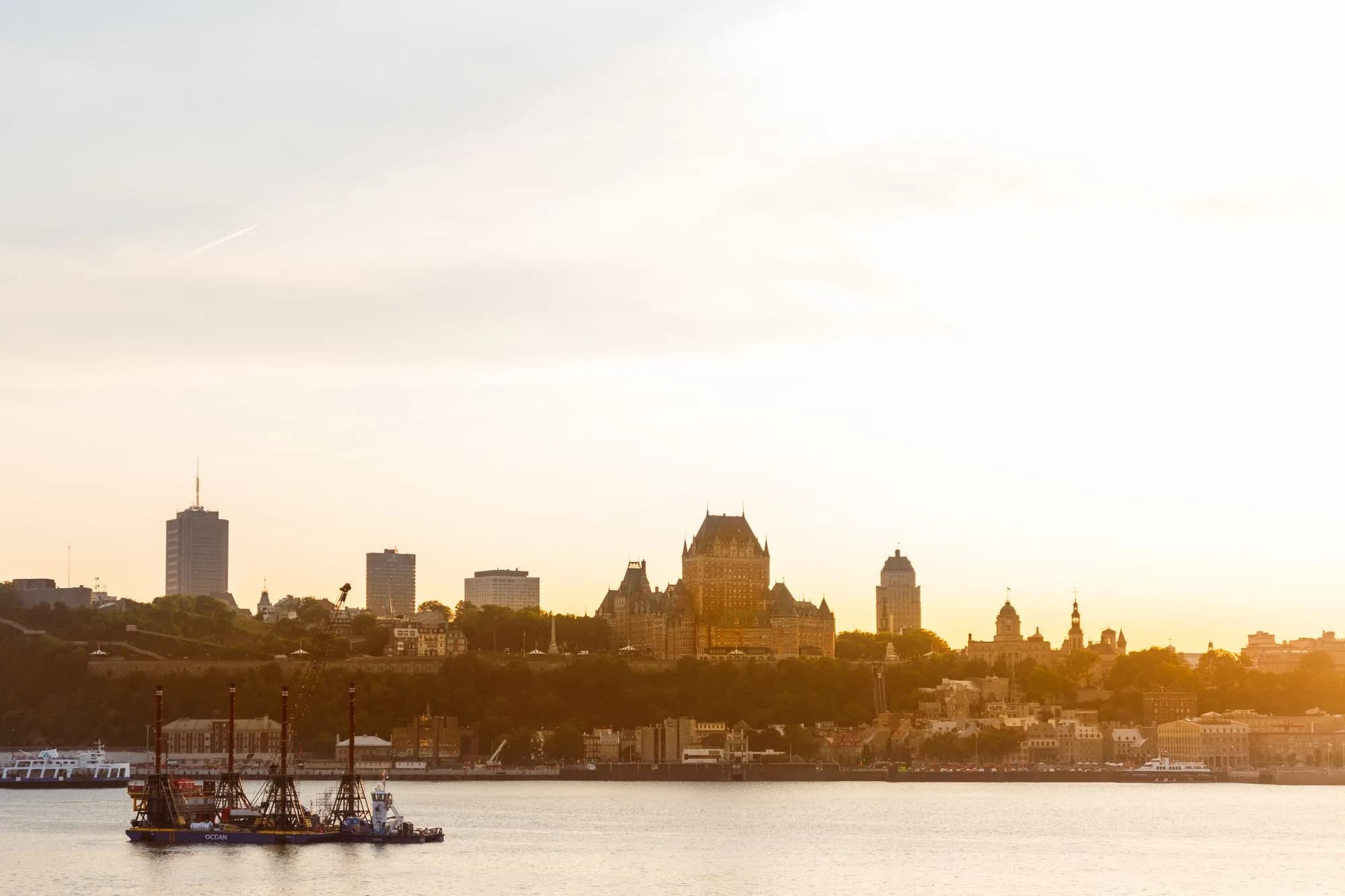 Québec City skyline and Château Frontenac beside the St. Lawrence River at golden hour.