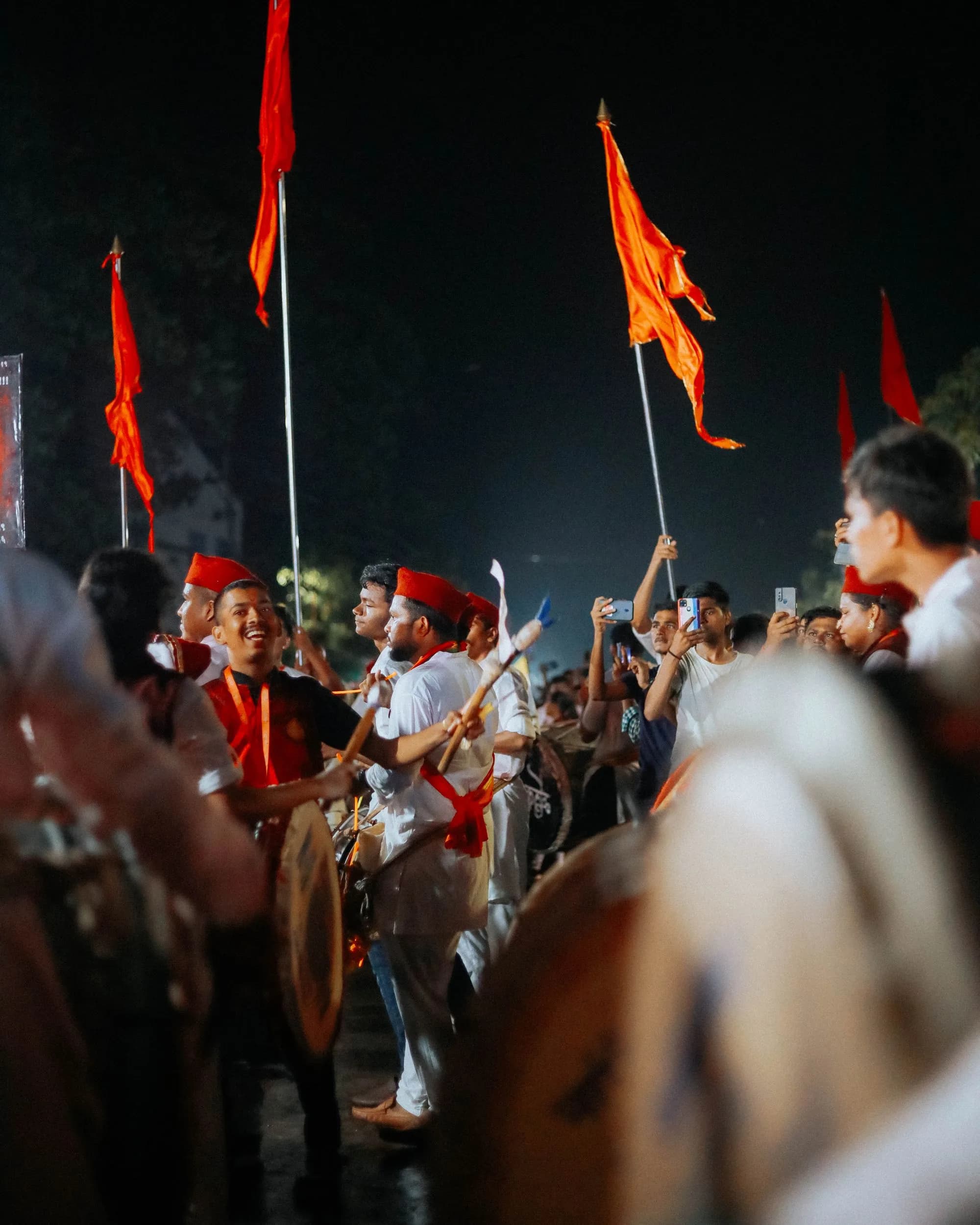 Energetic nighttime cultural festival with performers, flags and a gathered crowd.
